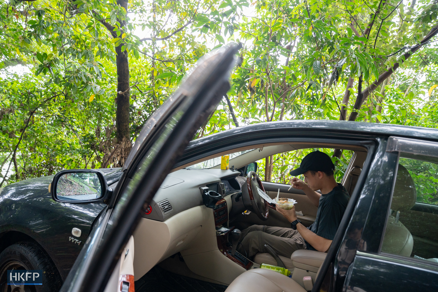 Fung enjoy his lunch in his car in the wild before shooting, the place was full of mosquitoes in Sai Kung district, 25 April 2025. Photo: Kyle Lam/HKFP.