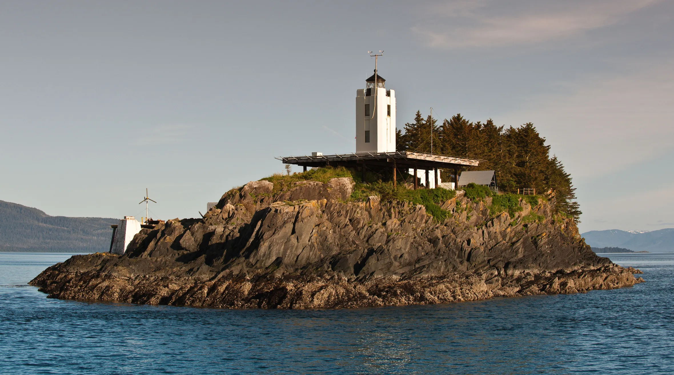 Five Finger Lighthouse on a rocky island with evergreen trees in Southeast Alaska.