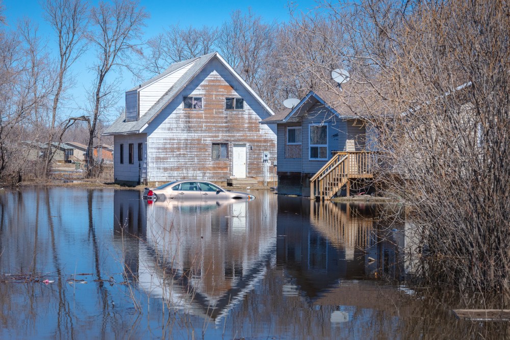 Flood waters surround a home and a car on Red Earth Cree Nation in northeastern Saskatchewan in this Wednesday, May 6, 2026 handout photo. THE CANADIAN PRESS/Handout - Tina Pelletier (Mandatory Credit)