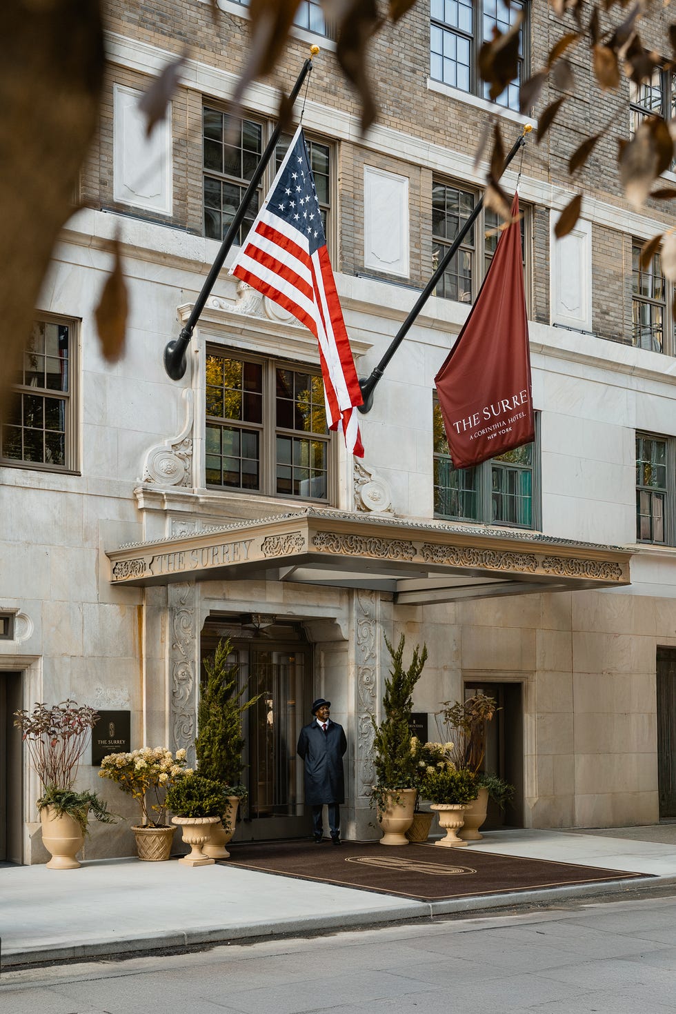 Entrance of The Surrey Hotel with flags and a doorman