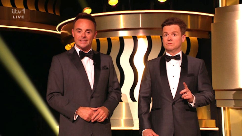 two men in tuxedos presenting on stage