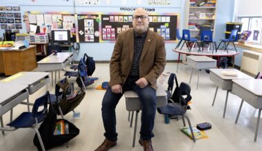English Montreal School Board chair Joe Ortona sits on a small desk in an elementary school classroom.