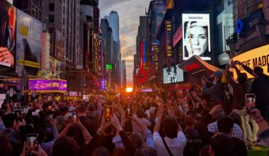 people taking photos of manhattanhenge with the sun setting lining up with the street