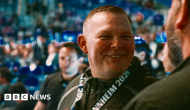 A smiley man in a crowd looks just right of the camera