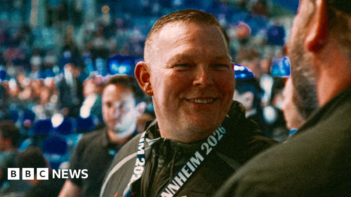 A smiley man in a crowd looks just right of the camera