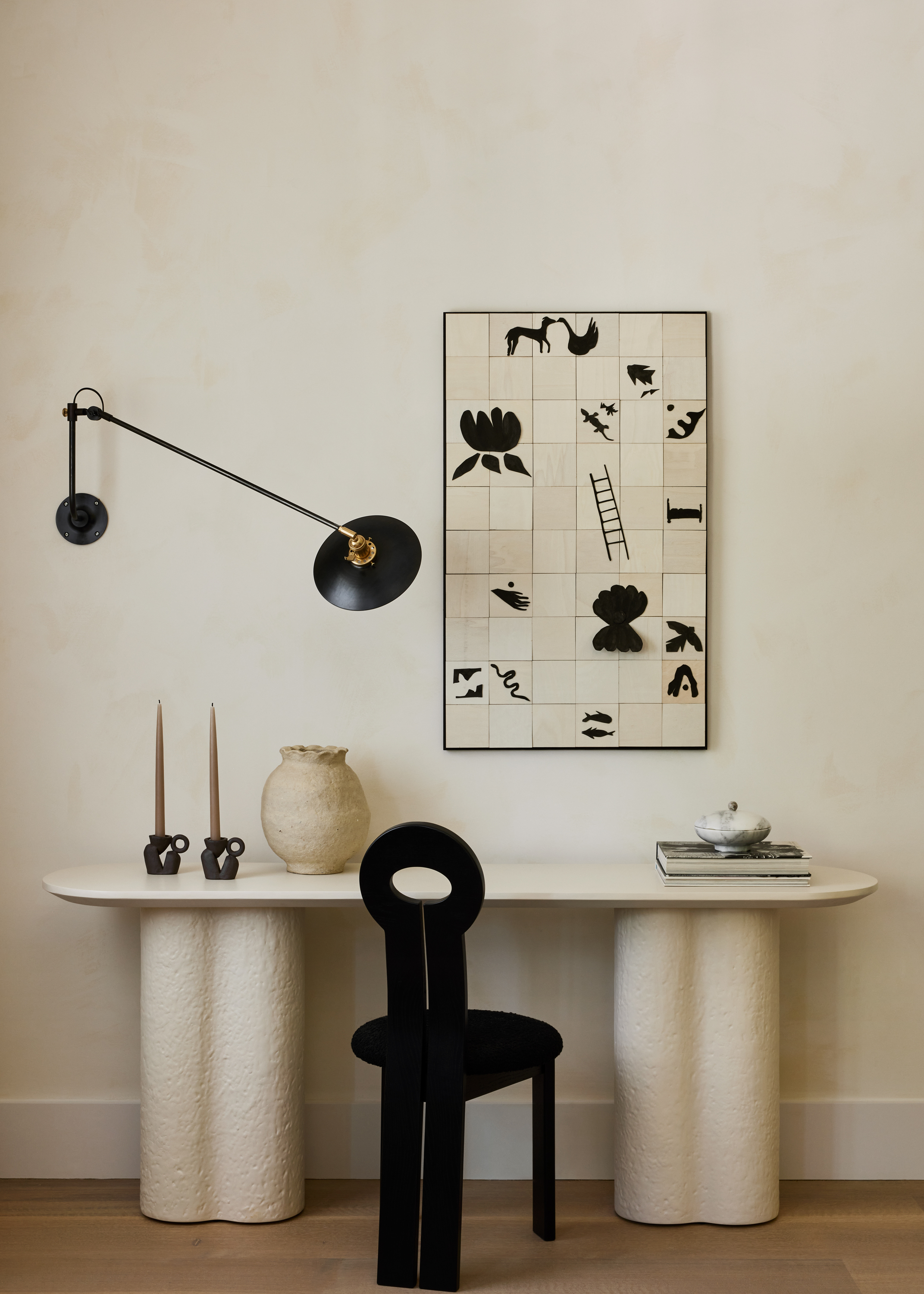 Interior shots depicting an apartment decorated with sculptural furnishings in earthy tones, framed artworks, marble and wood countertops, all bathing in natural light.