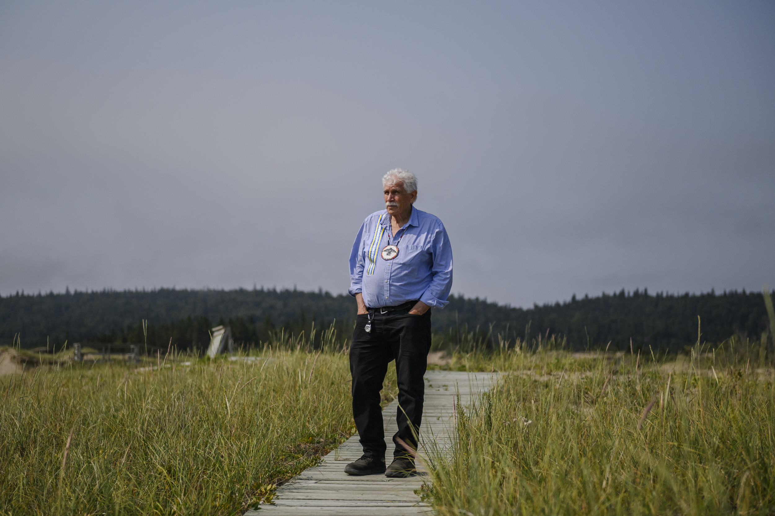 Lake Superior caribou: Duncan Michano stands with his hands in his pockets on a boardwalk passing over sand dunes and grasses