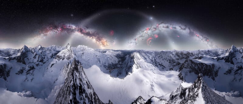 Snow-covered mountain peaks under a starry night sky, with bright arcs of the Milky Way and colorful nebulae stretching across the horizon.