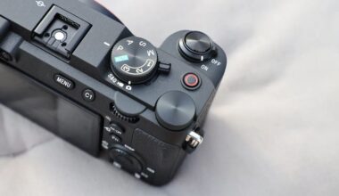 Close-up of a black digital camera's top controls including mode dial, shutter button, on/off switch, and menu buttons