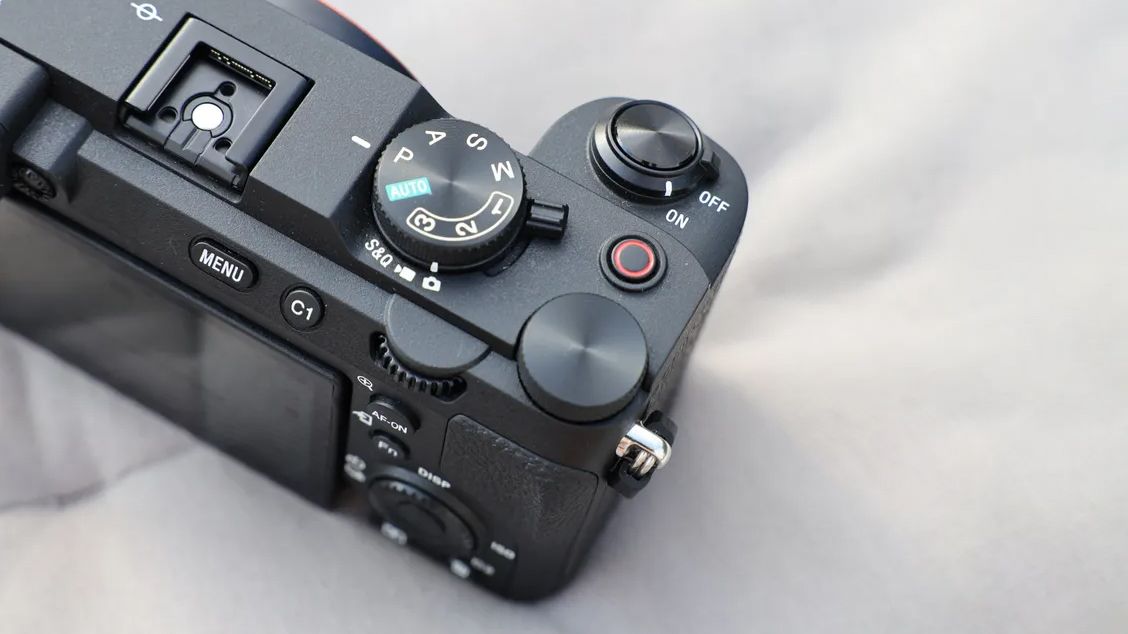 Close-up of a black digital camera's top controls including mode dial, shutter button, on/off switch, and menu buttons