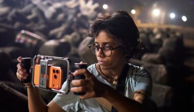 Person wearing glasses uses a handheld camera stabilizer to film outdoors at night.