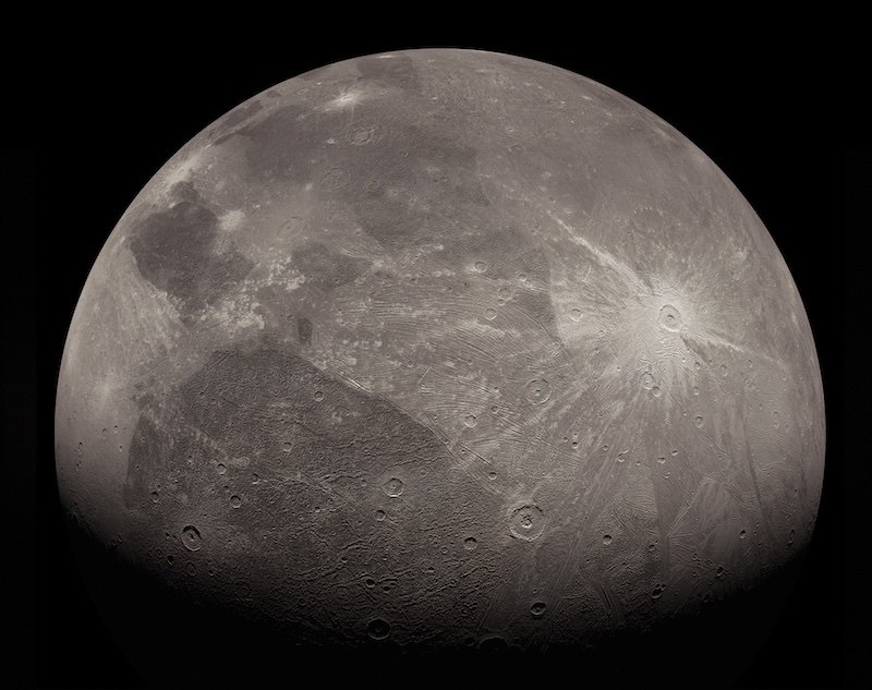 Ice volcanoes on Ganymede: Cratered, moon-like dark and light gray sphere with one large, bright white crater with rays.