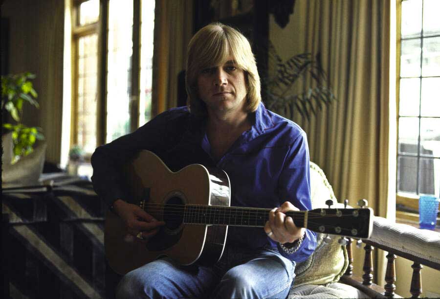 Justin Hayward at home in 1977, playing an acoustic guitar