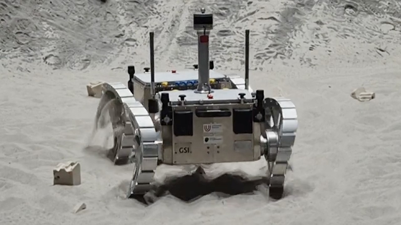 a four-wheeled vehicle drives on sand with curved wheels, leaving S-shaped tracks in the sand