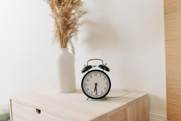 Black alarm clock and bed - stock photo