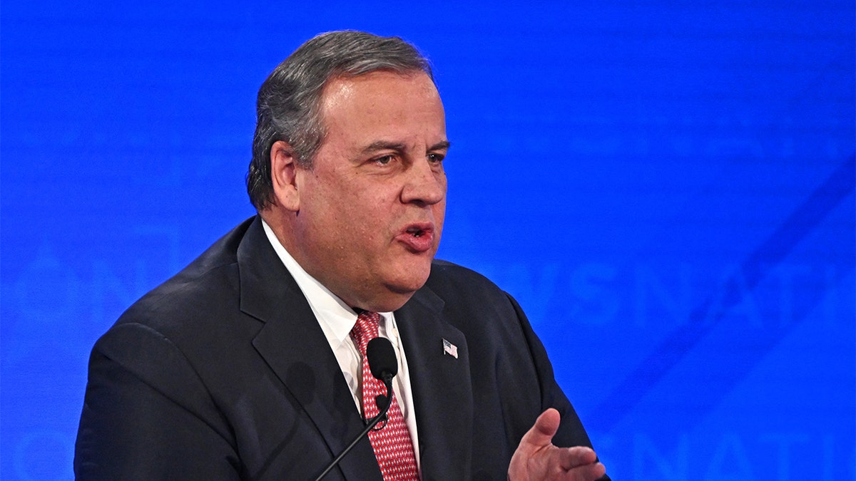 Former New Jersey Gov. Chris Christie gesturing while speaking at a debate stage