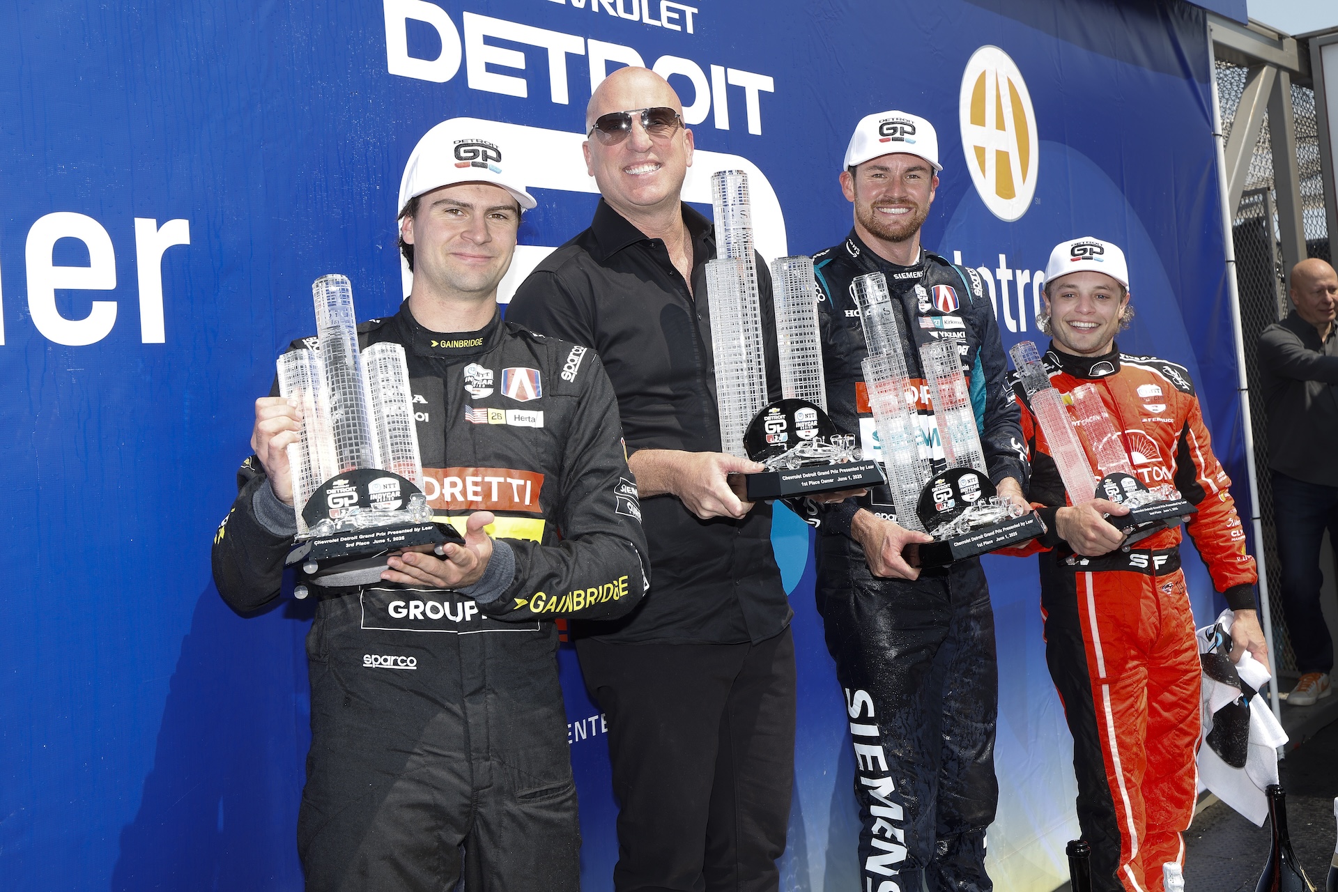 DETROIT, MICHIGAN - JUNE 1: #26: Colton Herta, Andretti Global w/ Curb-Agajanian Honda, Andretti owner Dan Towriss, #27: Kyle Kirkwood, Andretti Global Honda, #14: Santino Ferrucci, A.J. Foyt Enterprises Chevrolet, on the podium during the NTT IndyCar Series Chevrolet Detroit Grand Prix on June 1, 2025 in Detroit, Michigan. (Photo by Michael L. Levitt/Lumen via Getty Images)