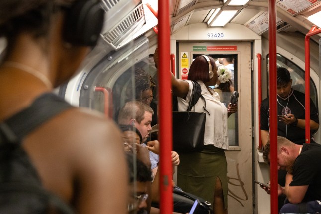 a woman holding a fan on an underground train