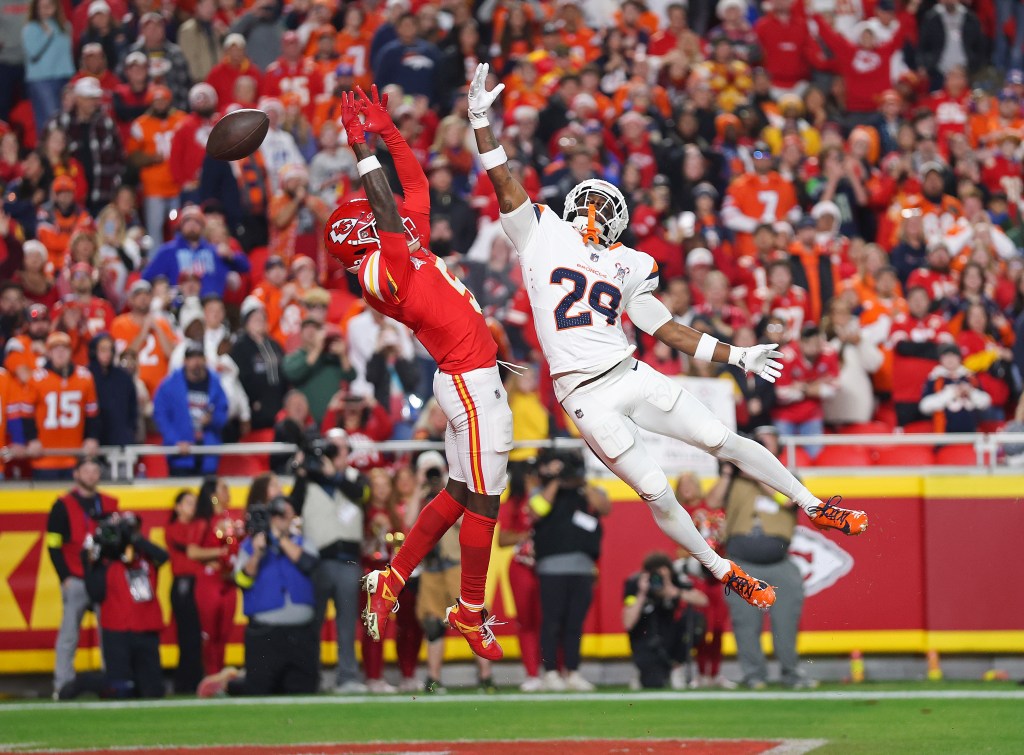 Kansas City Chiefs and Denver Broncos players jump to catch a football.