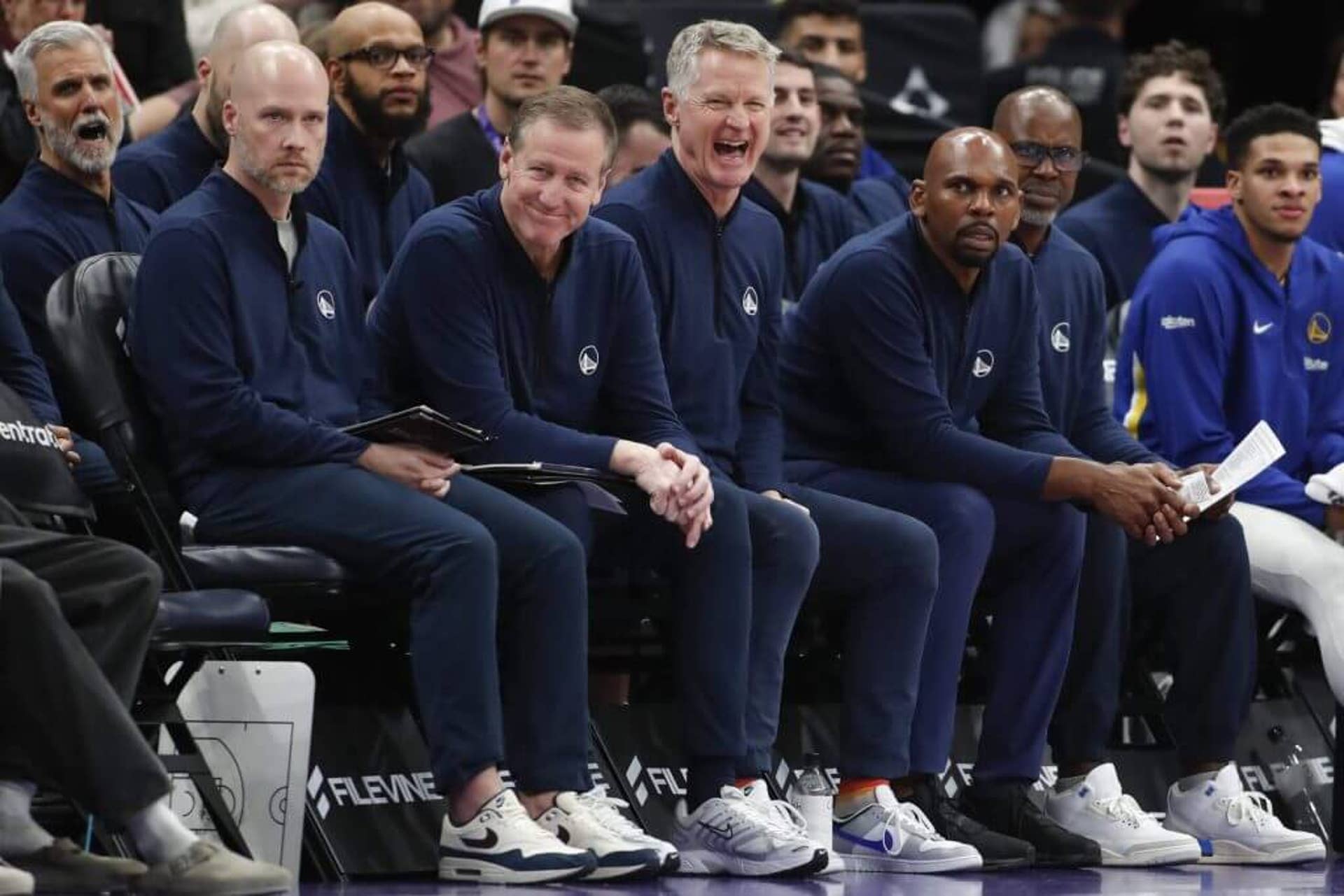 Golden State Warriors coaches sit on the sideline during a game. From left to right: Seth Cooper, Terry Stotts, Steve Kerr, Jerry Stackhouse and Kris Weems.