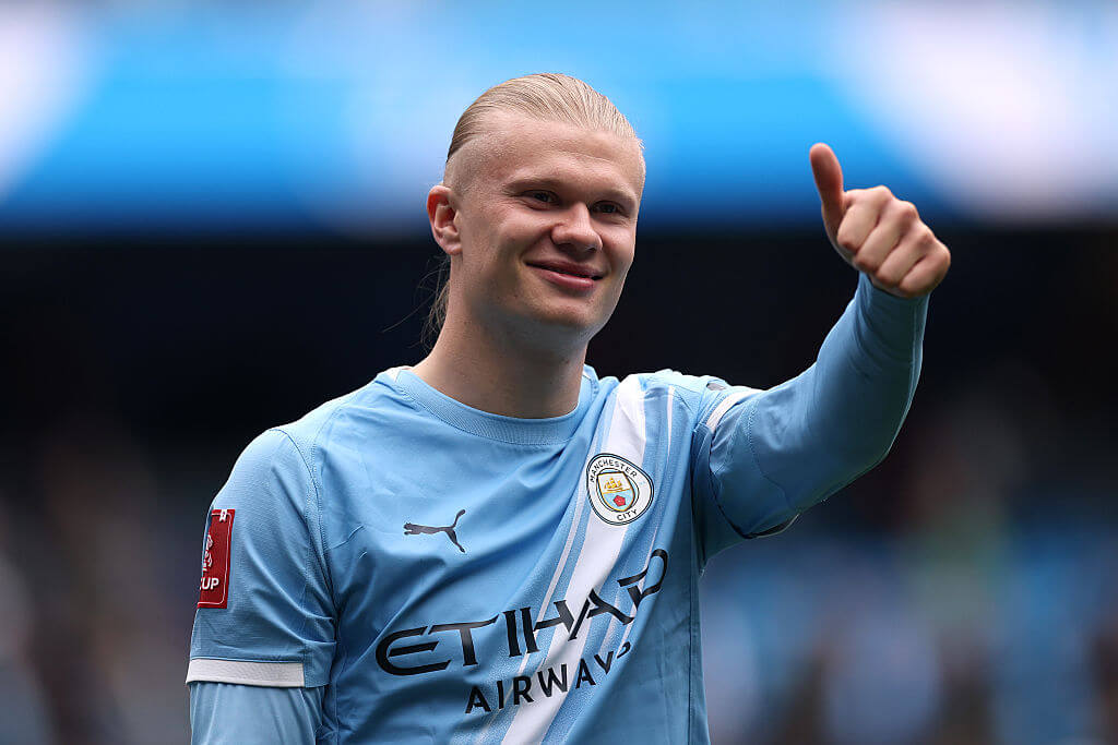 Manchester City striker Erling Haaland holding a thumbs up to team-mates