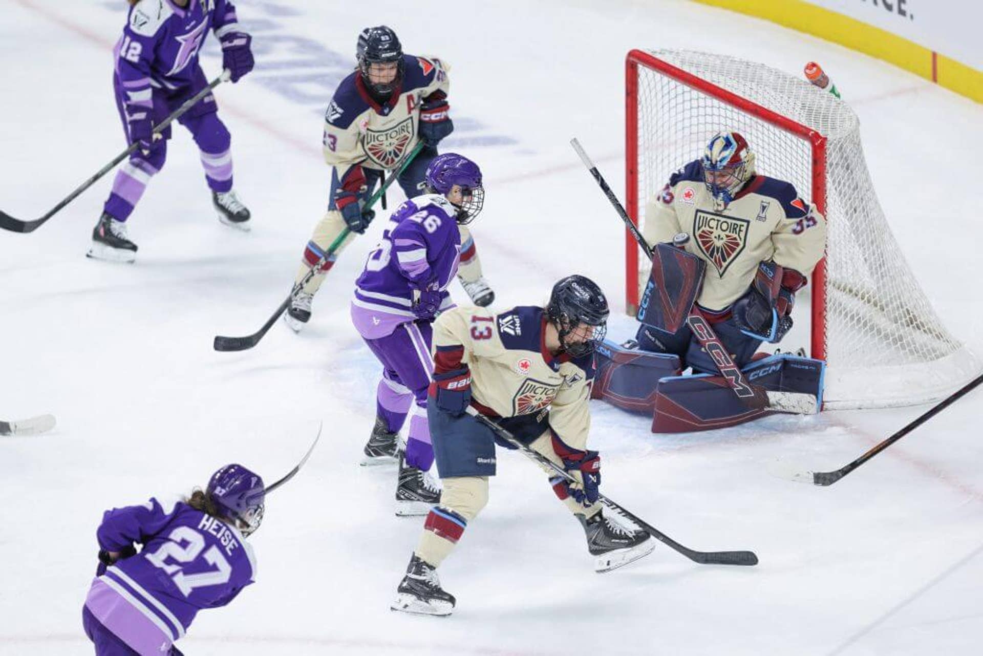 Montréal Victoire forward Lina Ljungblom makes a save on a shot from Minnesota Frost forward Taylor Heise during a playoff game as others crowd around the net.