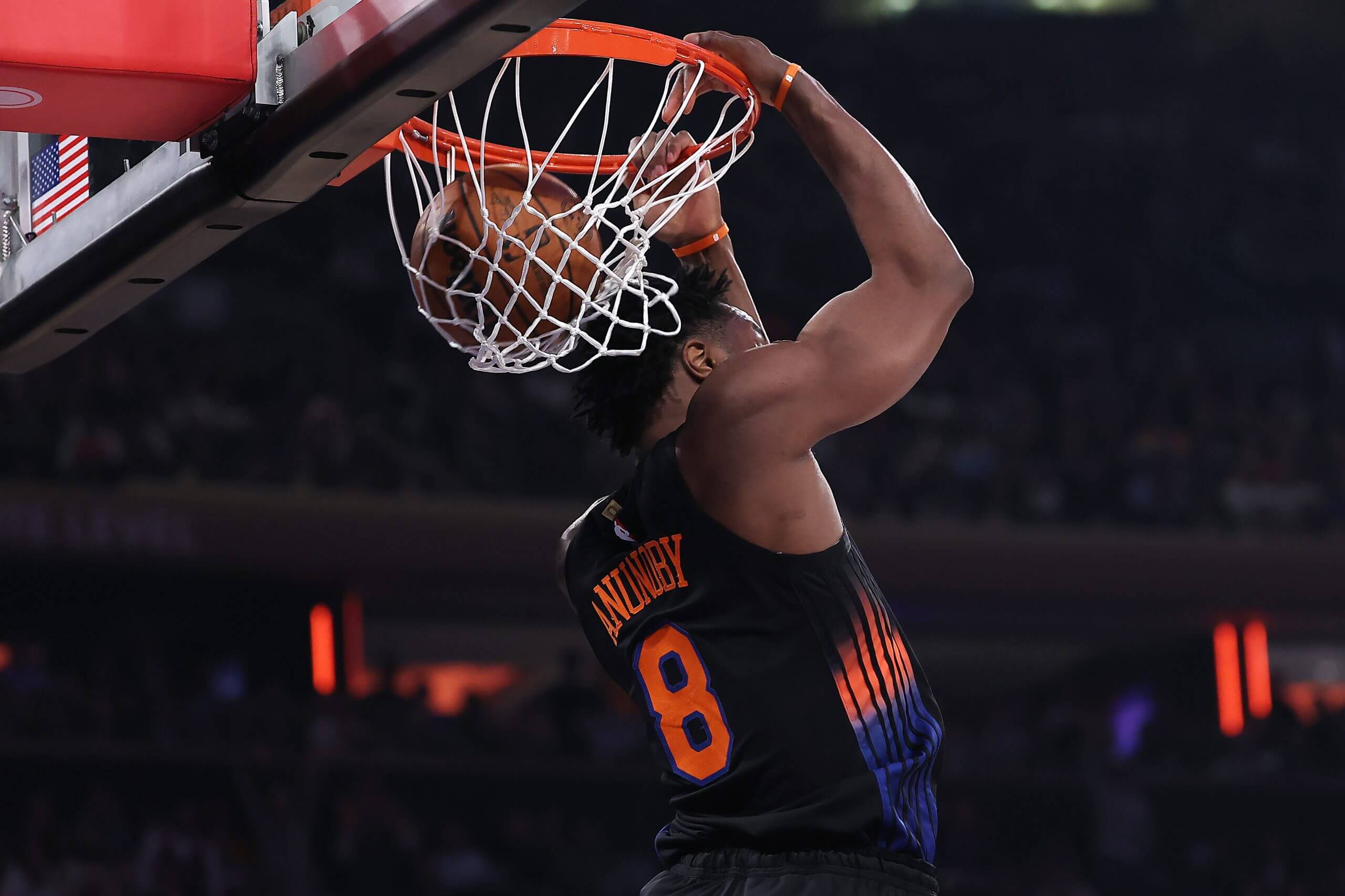 Knicks forward OG Anunoby hangs off the rim with his back to the basket against the 76ers.