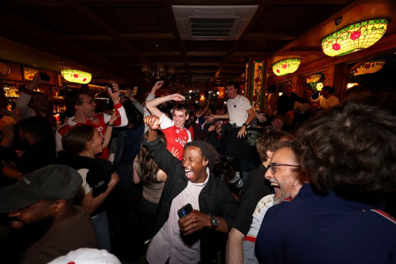 Fans of Arsenal celebrate as Arsenal are confirmed as Premier League champions following Manchester City's 1-0 defeat to AFC Bournemouth, as they gather at The Drayton Park Arms in London