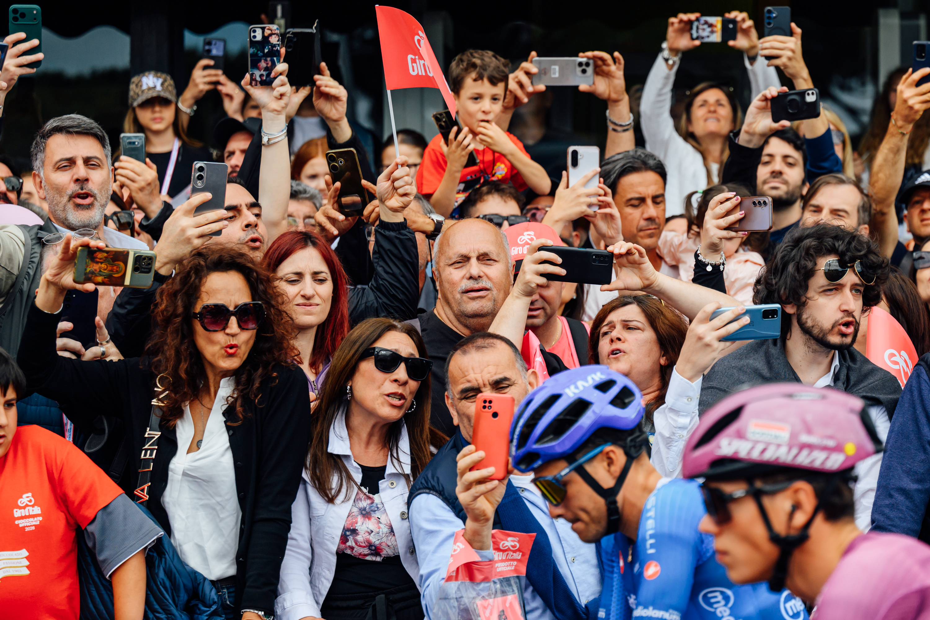 Fans taking selfies at the start line where the peloton awaits the start of the race. Images from 2026 Giro d'Italia stage 7 to Blockhaus
