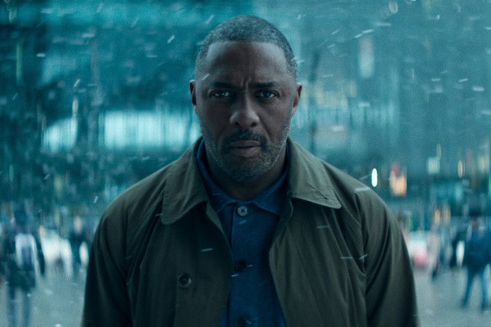 Idris Elba standing in the street while snow falls around him in Hijack season 2.
