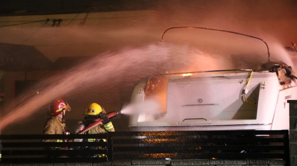 Firefighters spray water on boat fire