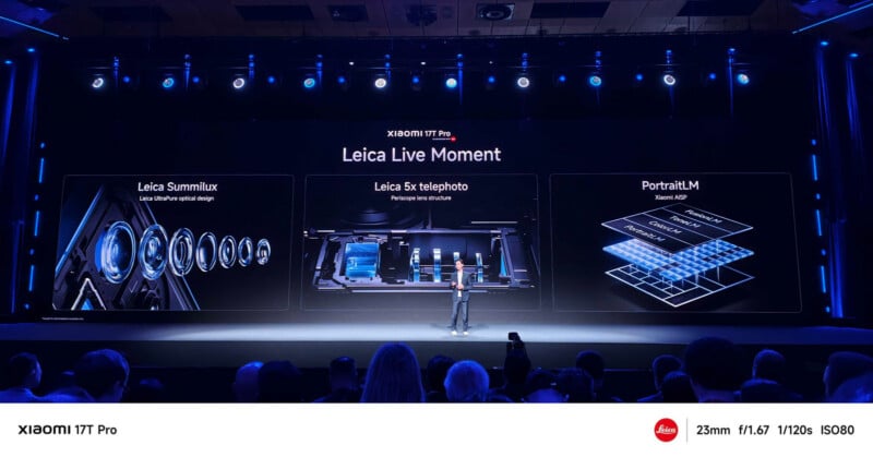 A presenter stands on a stage in front of a large screen showing three sections about Xiaomi 13T Pro’s Leica camera features: Summilux lens, 5x telephoto, and Portrait LM. The audience is faintly visible.