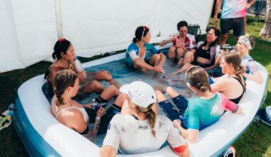 A group of pro female triathletes sit in a children's inflatable pool filled with water and ice to recover after a triathlon.