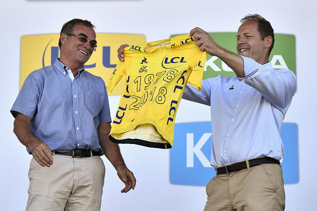 Christian Prudhomme holds a Tour de France yellow jersey alongside the last French Tour winner, Bernard Hinault
