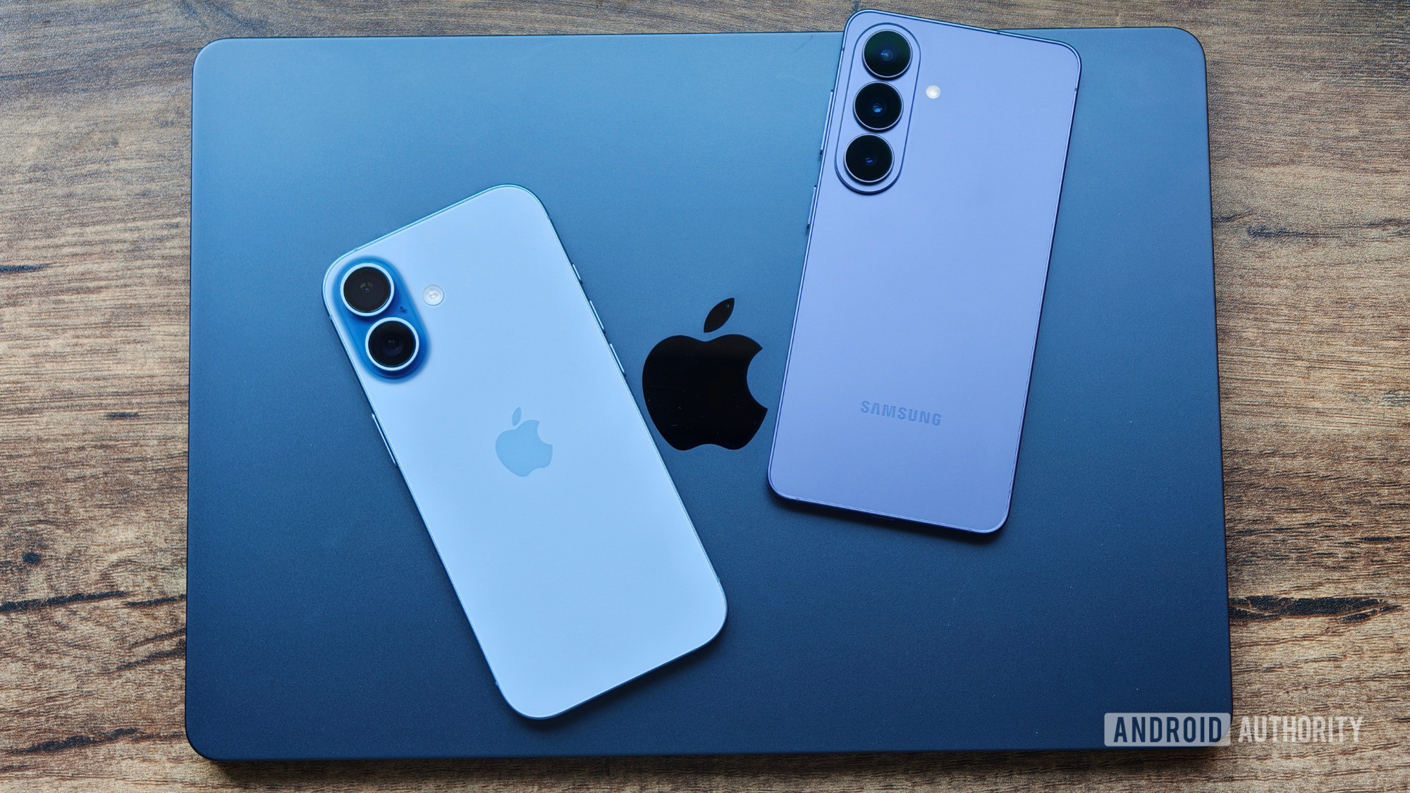 MacBook on table with iPhone 17 and Galaxy S26 on top of it MacBook on table with iPhone 17 and Galaxy S26 on top of it