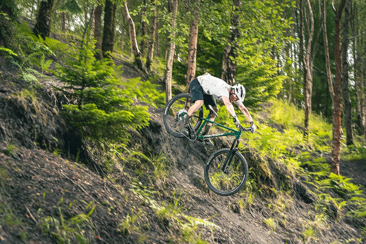 Male rider in white top riding the Merida Big.Trail 600 hardtail mountain bike