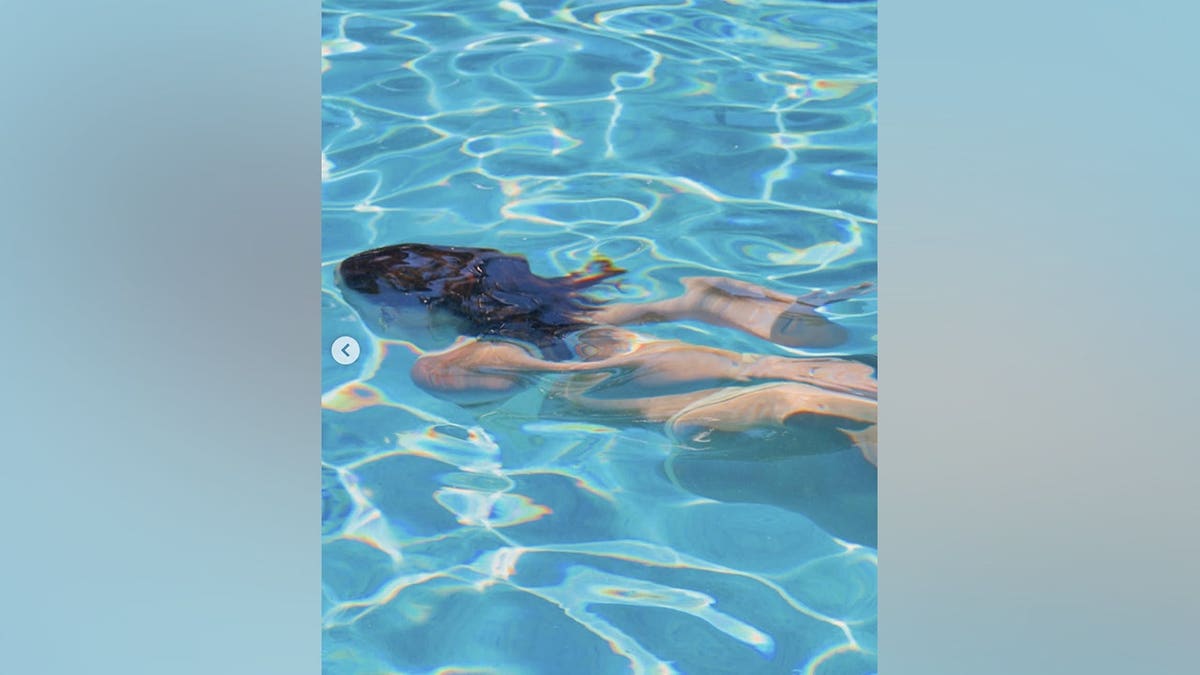 Millie Bobby Brown floats underwater in a pool while wearing a yellow bikini.