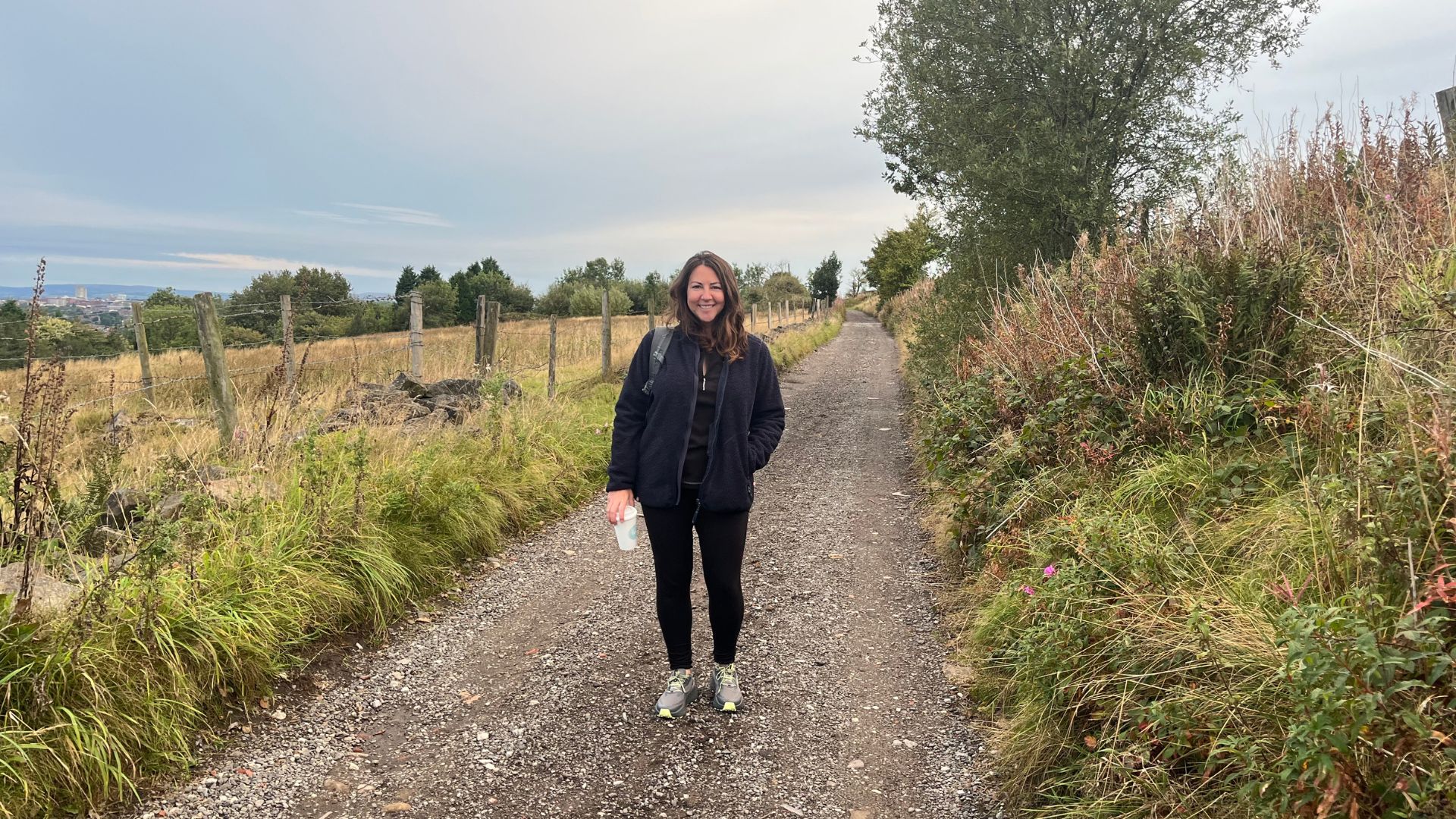 Susan Griffin doing 10-minute walking workout on countryside path, smiling and wearing workout clothes