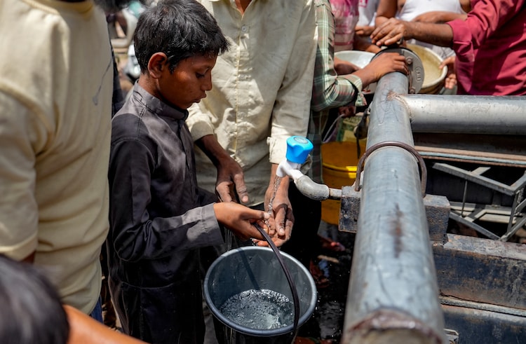A young boy fills a container with water during a heatwave in New Delhi. (Photo: PTI)