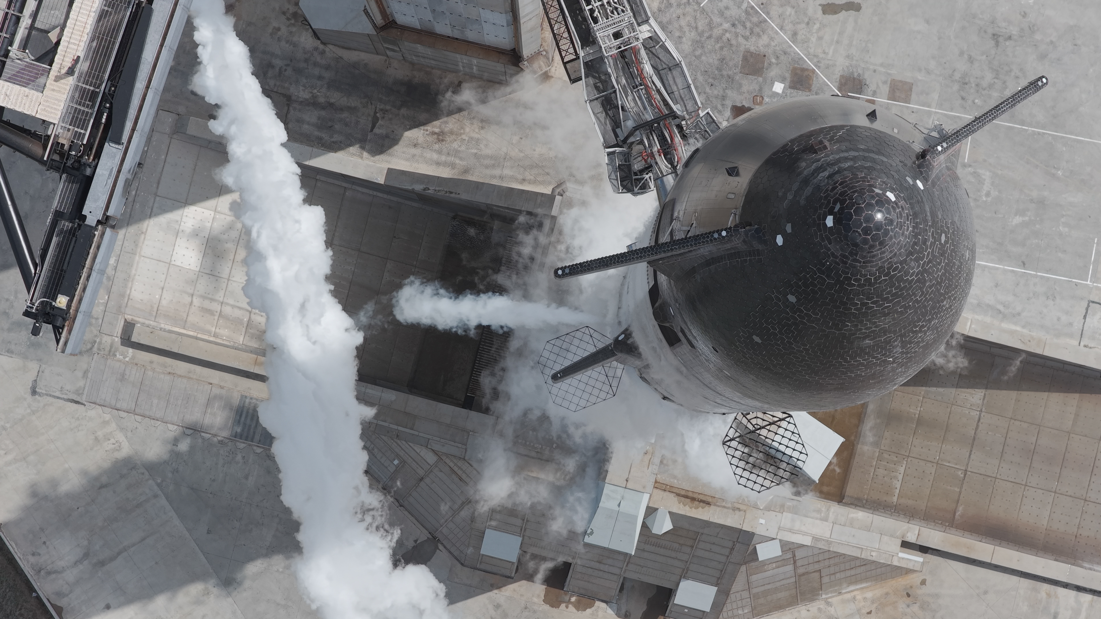 drone photo looking down at the conical black nose of a large rocket on a launch pad