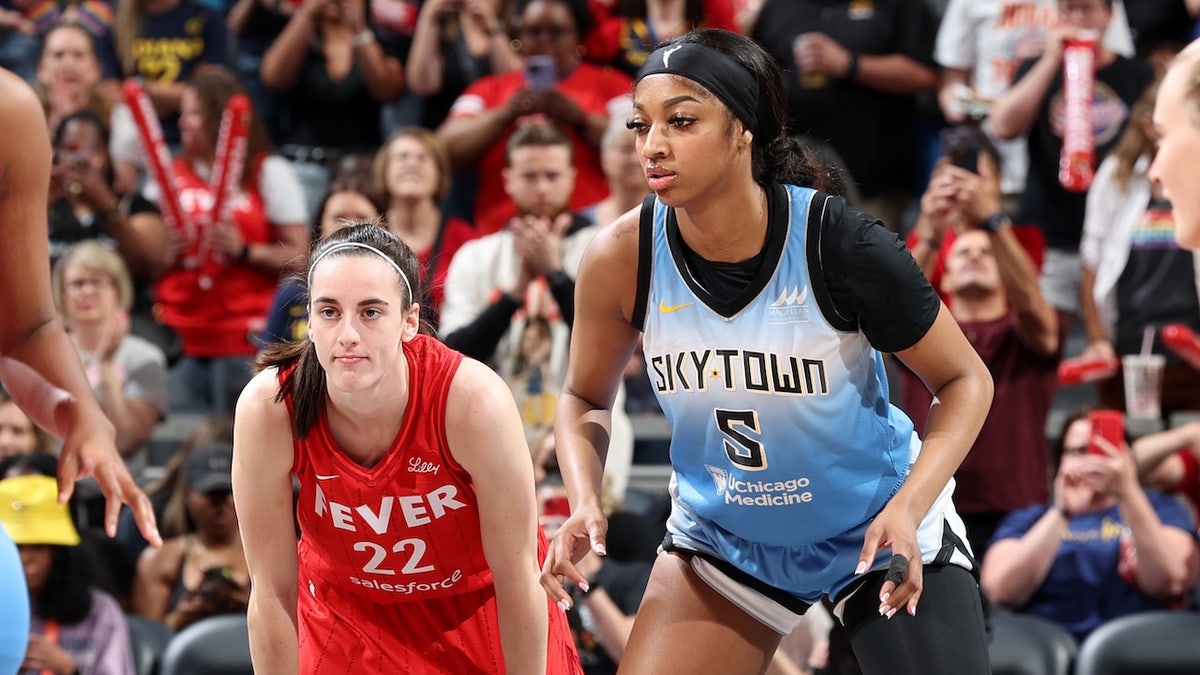 Caitlin Clark and Angel Reese standing on basketball court during game
