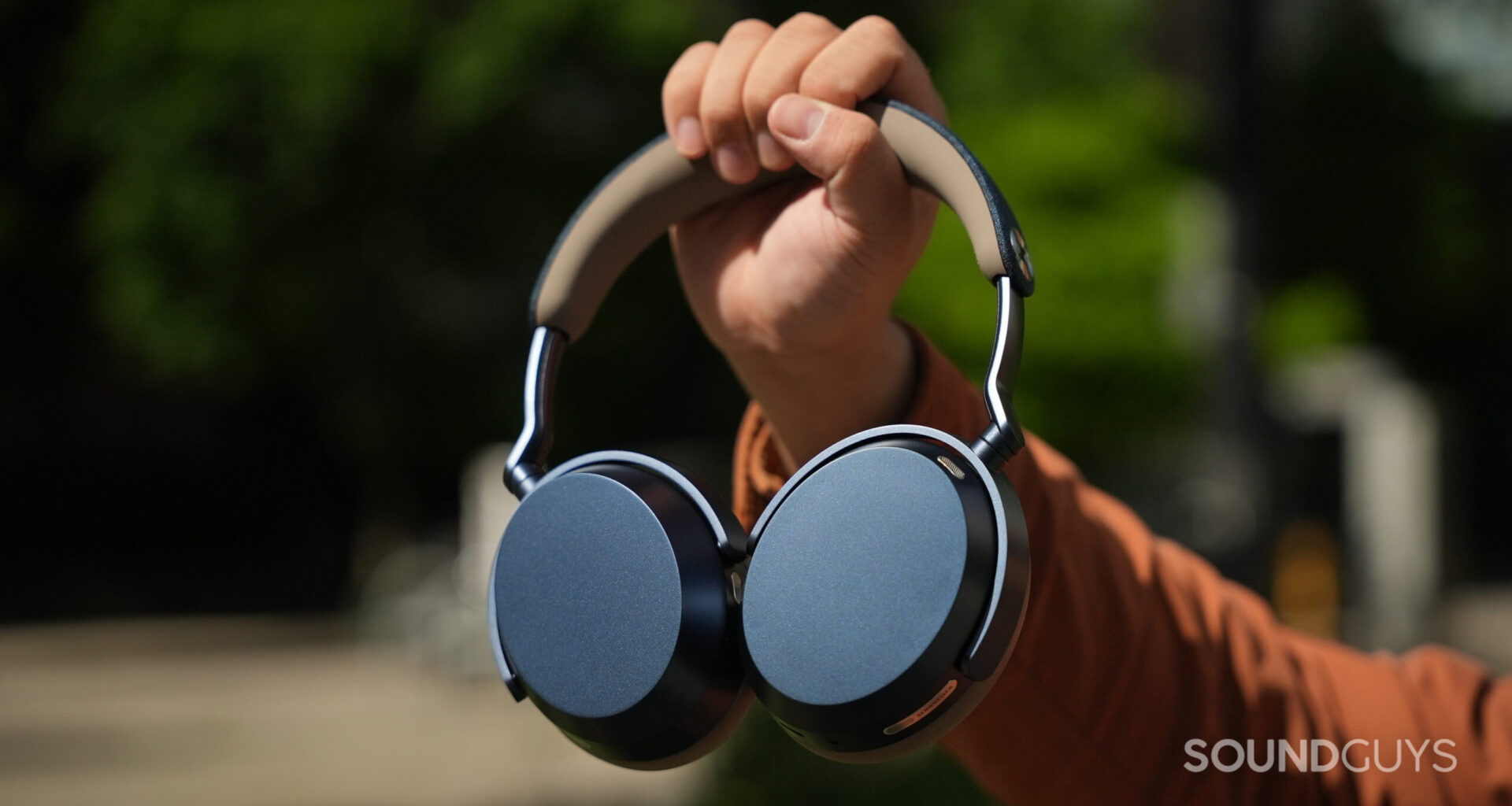 A photo of someone holding the Sennheiser MOMENTUM 5 Wireless headphones at arm's length.