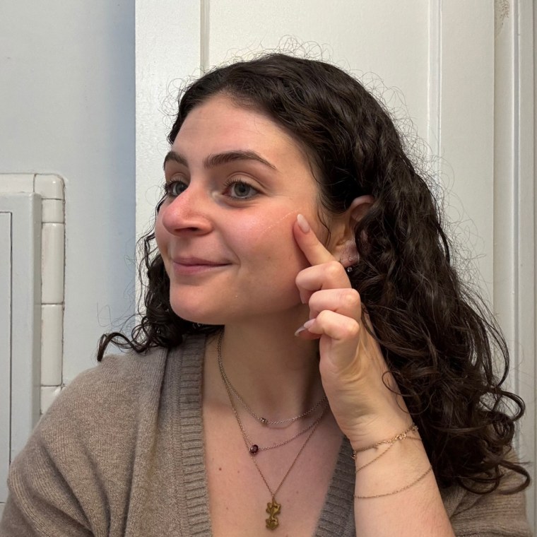 A woman applying Summer Fridays’ CC Me Serum.