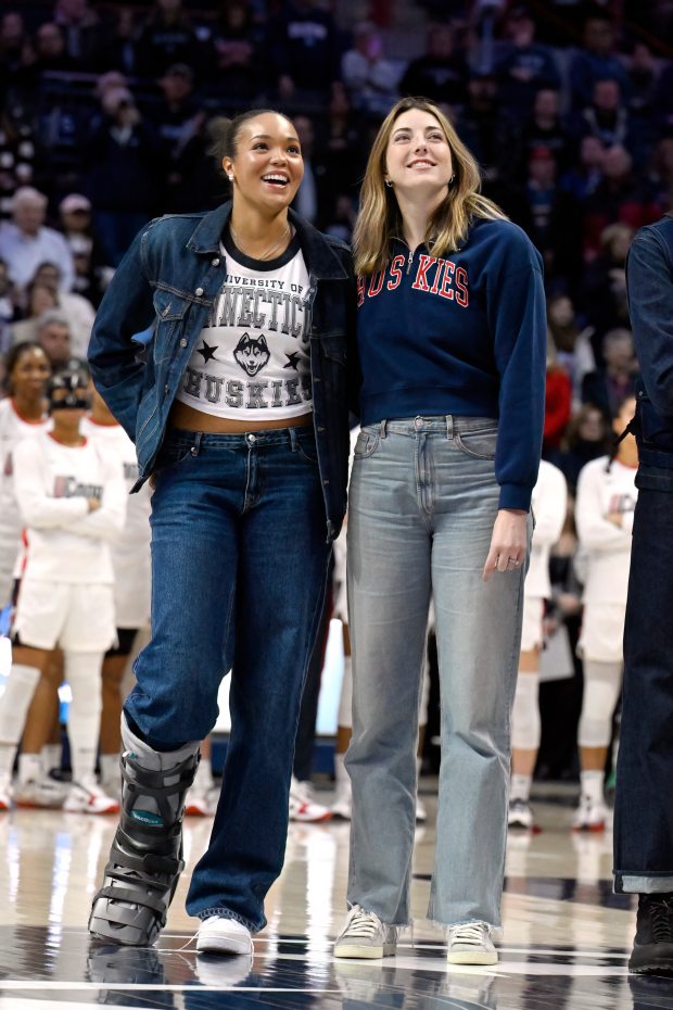 Former UConn players and WNBA players Napheesa Collier, left, and Katie Lou Samuelson watch a video screen during a pregame ceremony honoring the UConn 2015 and 2016 championship basketball teams before an NCAA college basketball game, Thursday, Jan. 15, 2026, in Storrs, Conn. (AP Photo/Jessica Hill)