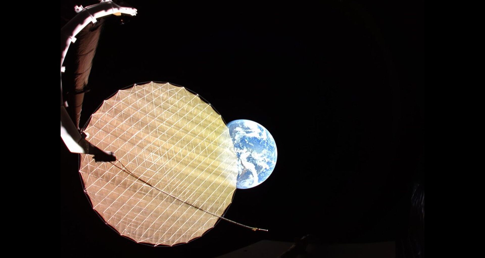 Earth photobombs a satellite deploying its giant reflector photo of the day for May 14, 2026
