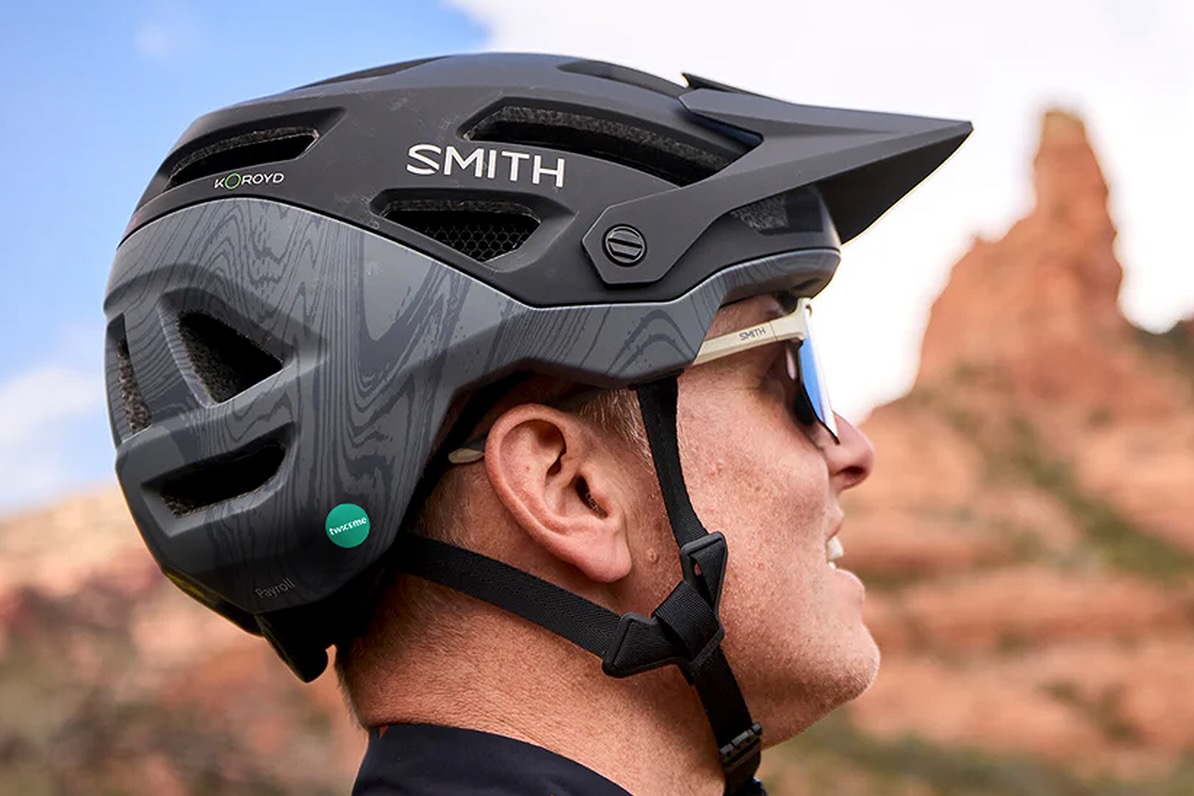 a man wearing the Smith Payroll Twiceme helmet with desert rocks in the background.