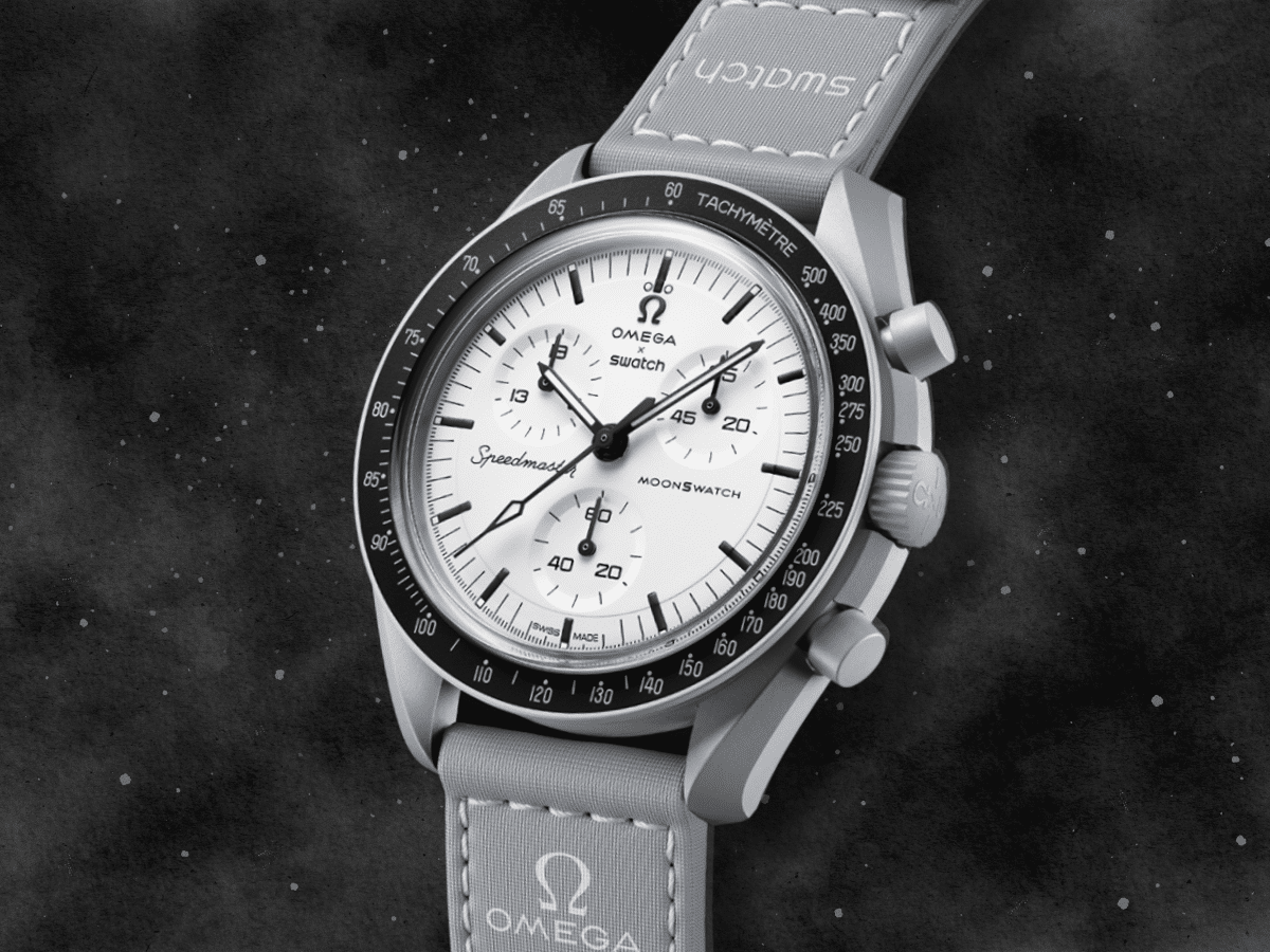 Omega x Swatch MoonSwatch 1965 watch with a white dial, black tachymeter bezel, and grey strap against a starry background.