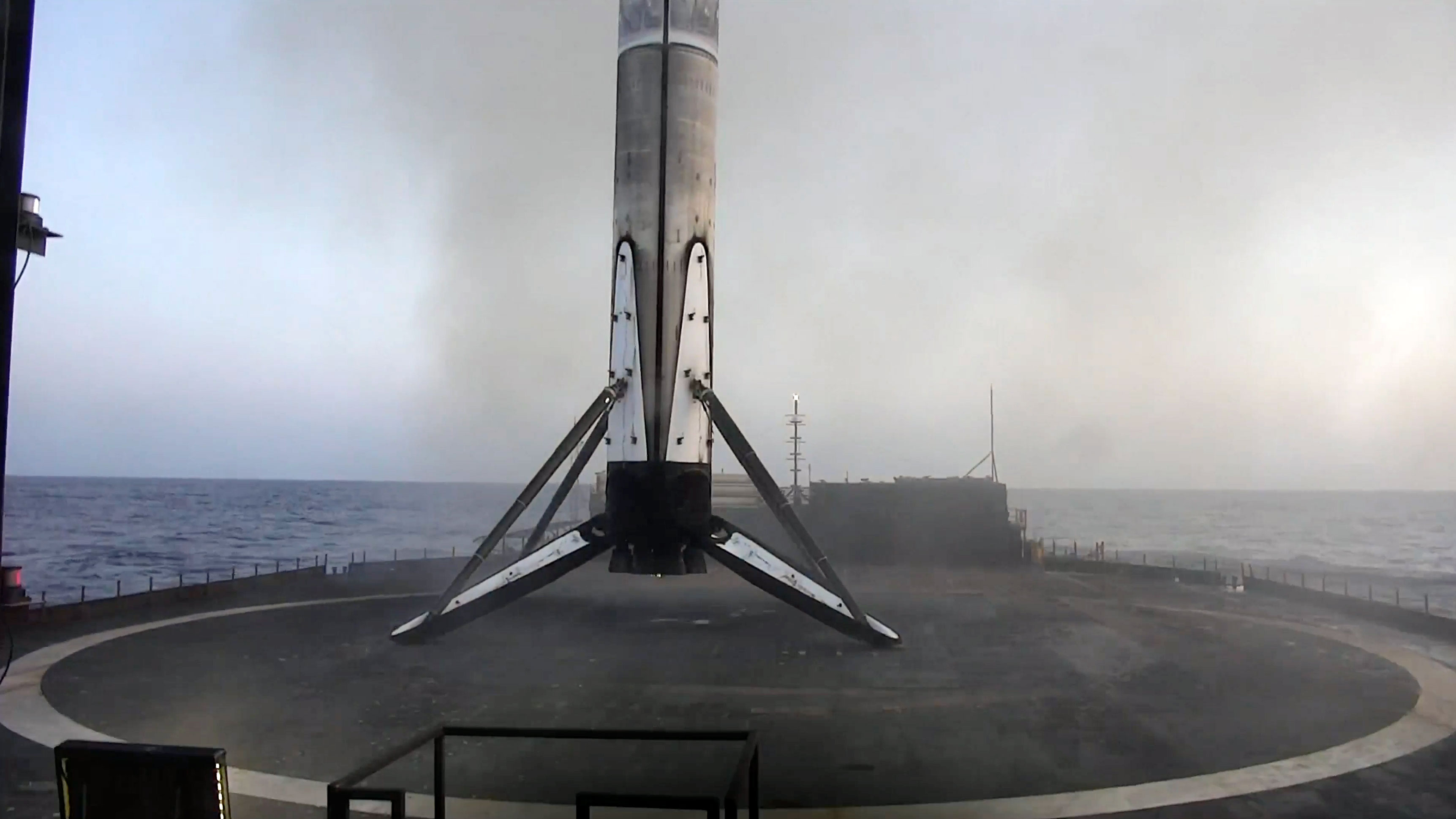 standing on its four deployed legs atop an ocean based droneship, a rocket's first stage is seen standing upright after returning from space.