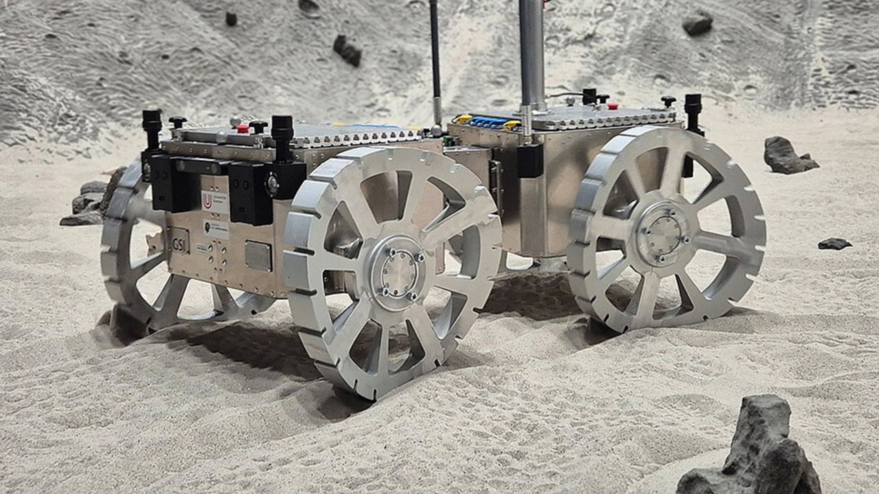 a four-wheeled vehicle with curved wheels drives through deep, loose sand
