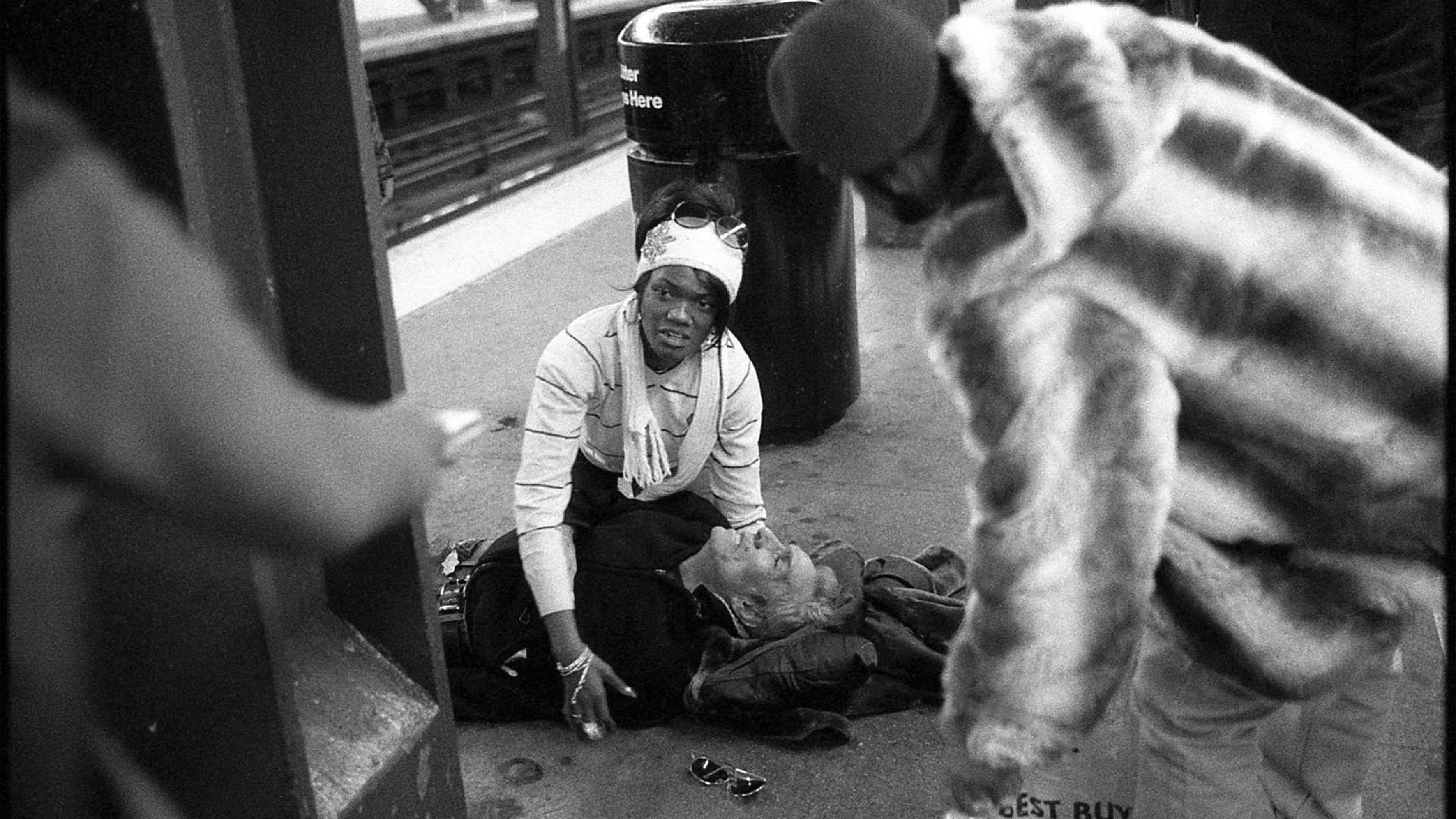 A woman helps a seemingly unconscious man.
